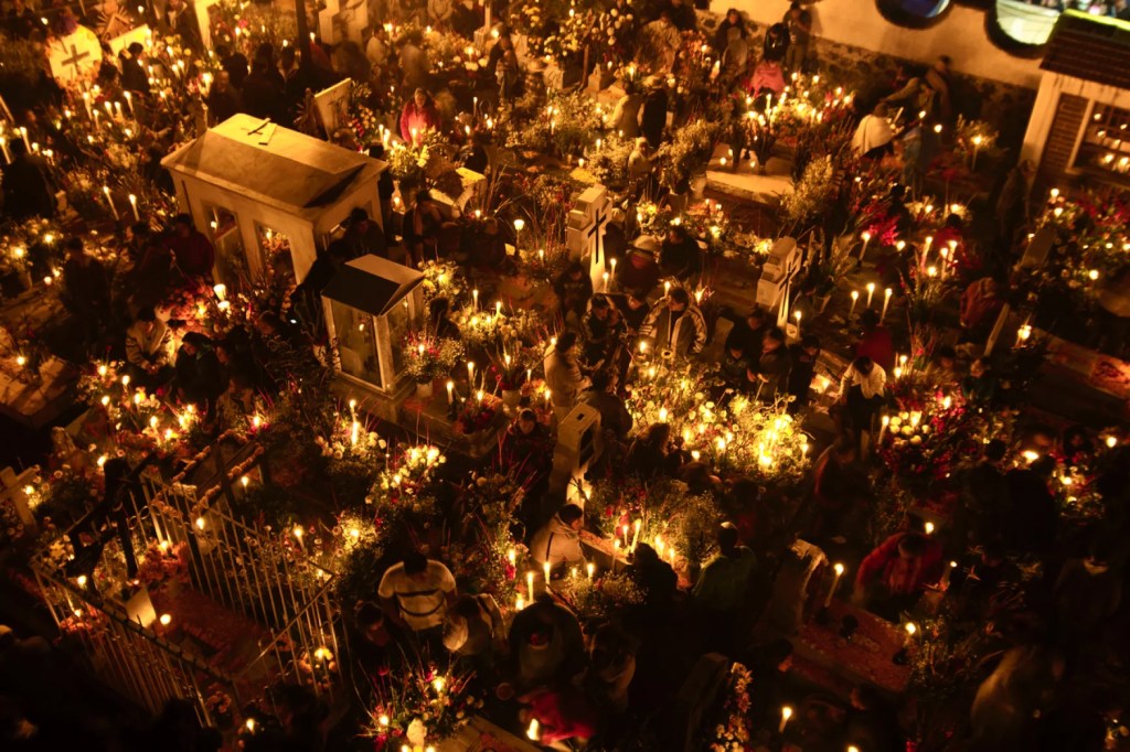 Vista aérea de Mixquic iluminado con cientos de velas y ofrendas durante la noche del Día de Muertos en México.