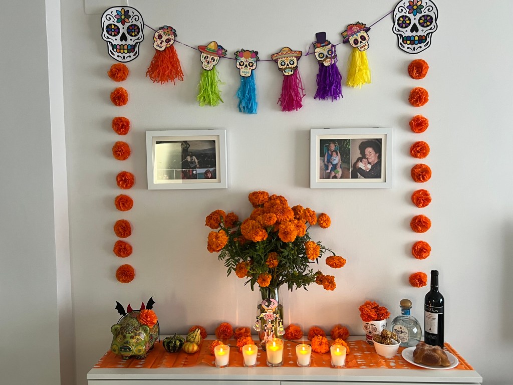 Altar de muertos con flores de cempasúchil, velas, papel picado y fotografías familiares, montado en una casa en Cataluña.