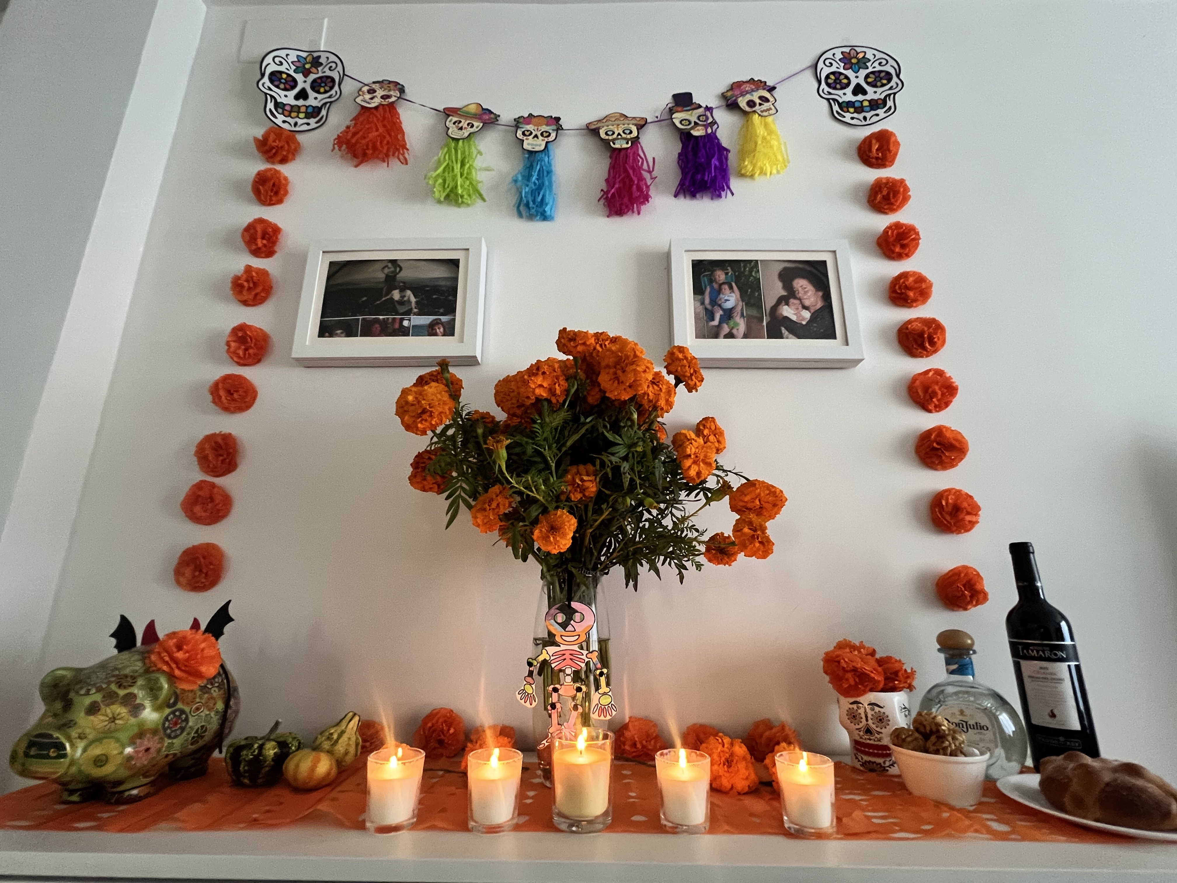 Altar de muertos con flores de cempasúchil, velas, papel picado y fotografías familiares, montado en una casa en Cataluña.