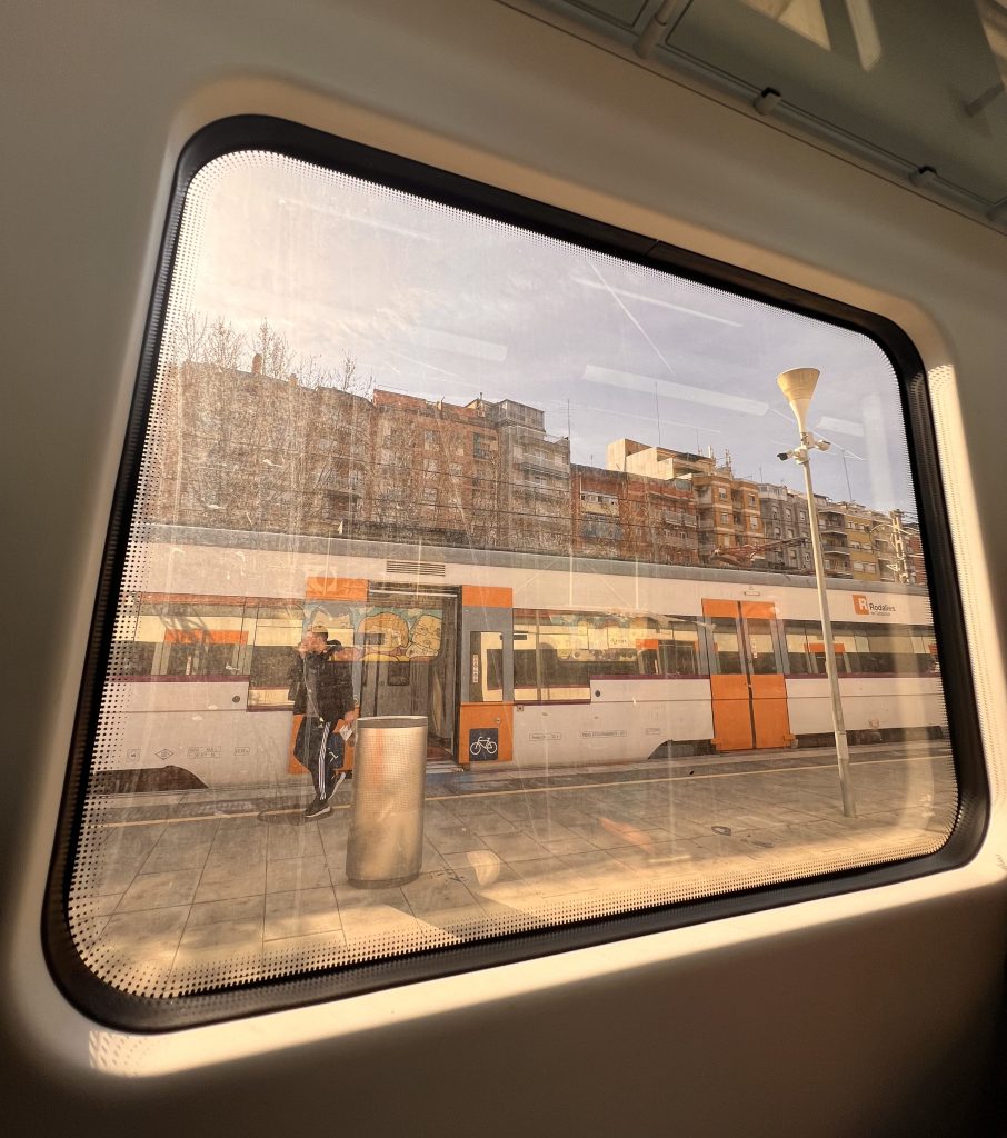 Vista desde la ventana de un tren en Barcelona con edificios de la ciudad al fondo