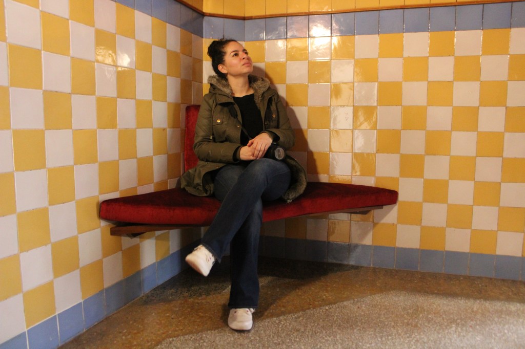 Mujer sentada en un banco en una estación de metro de Barcelona reflexionando sobre emigrar y vivir fuera de su país