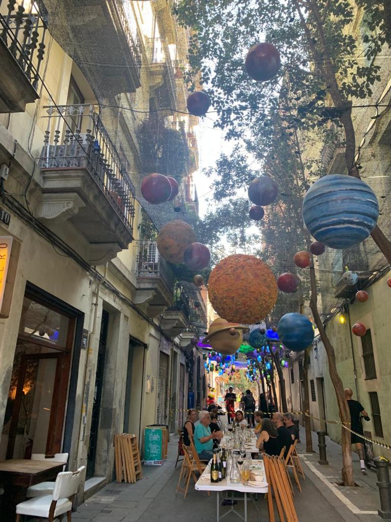 Vecinos compartiendo una comida en una calle decorada durante las Fiestas de Gràcia