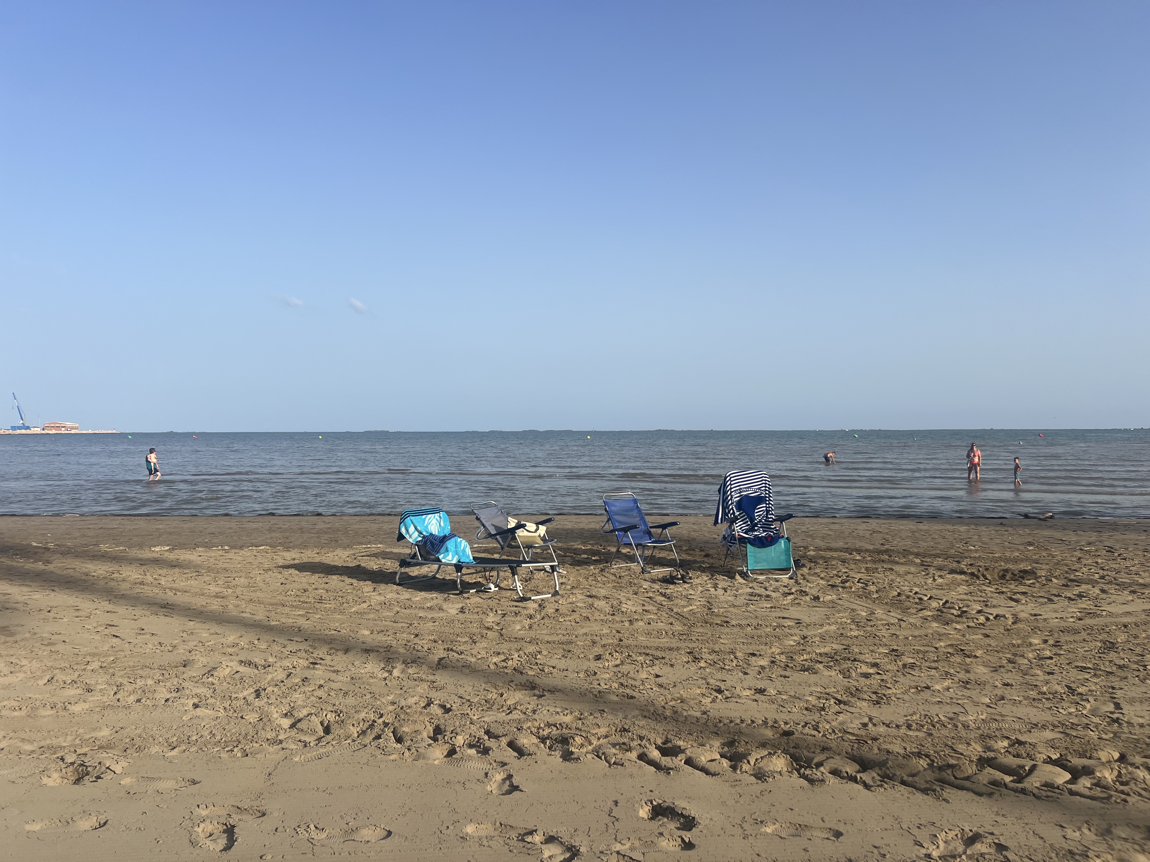 Sombrilla de colores, bañistas y palmeras en una playa española durante el verano